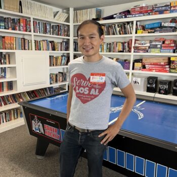 male volunteer standing in front of a bookcase smiling
